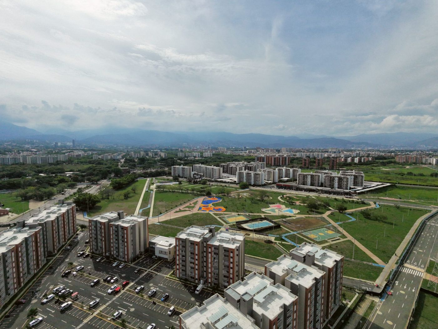 Parque con canchas deportivas y juegos infantiles junto a torres de apartamentos